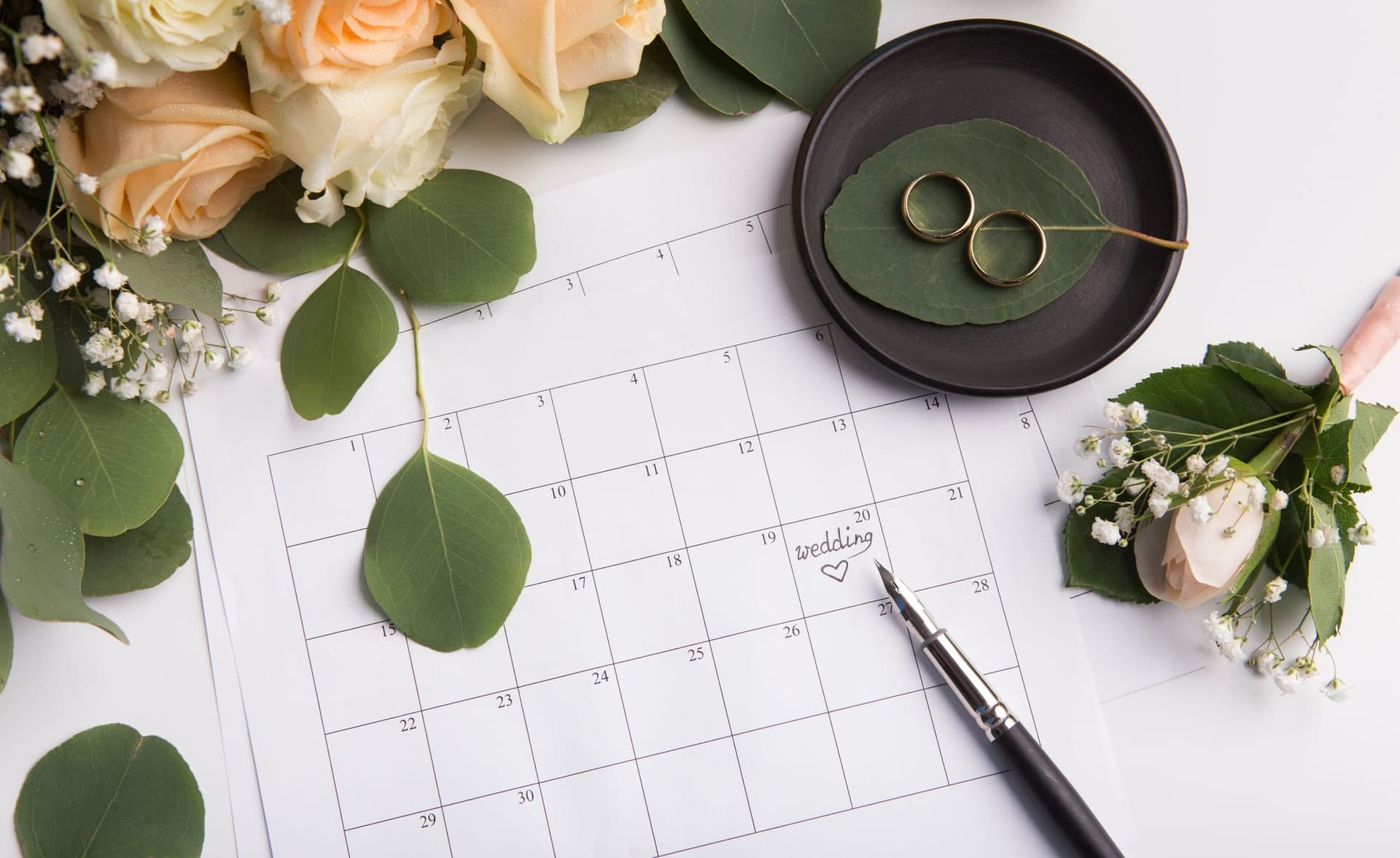 Anillos de boda junto a un calendario para organizar la fecha