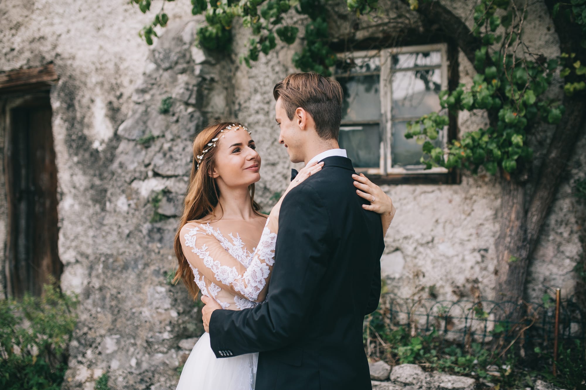 Novios abrazándose junto a un edificio de piedra el día de su boda